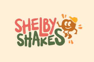 The image showcases "Shelby Shakes" in bold, playful red and green letters. Beside it, a cheerful cartoon character with an orange cap smiles and jumps energetically against a light beige background, radiating a joyful vibe.