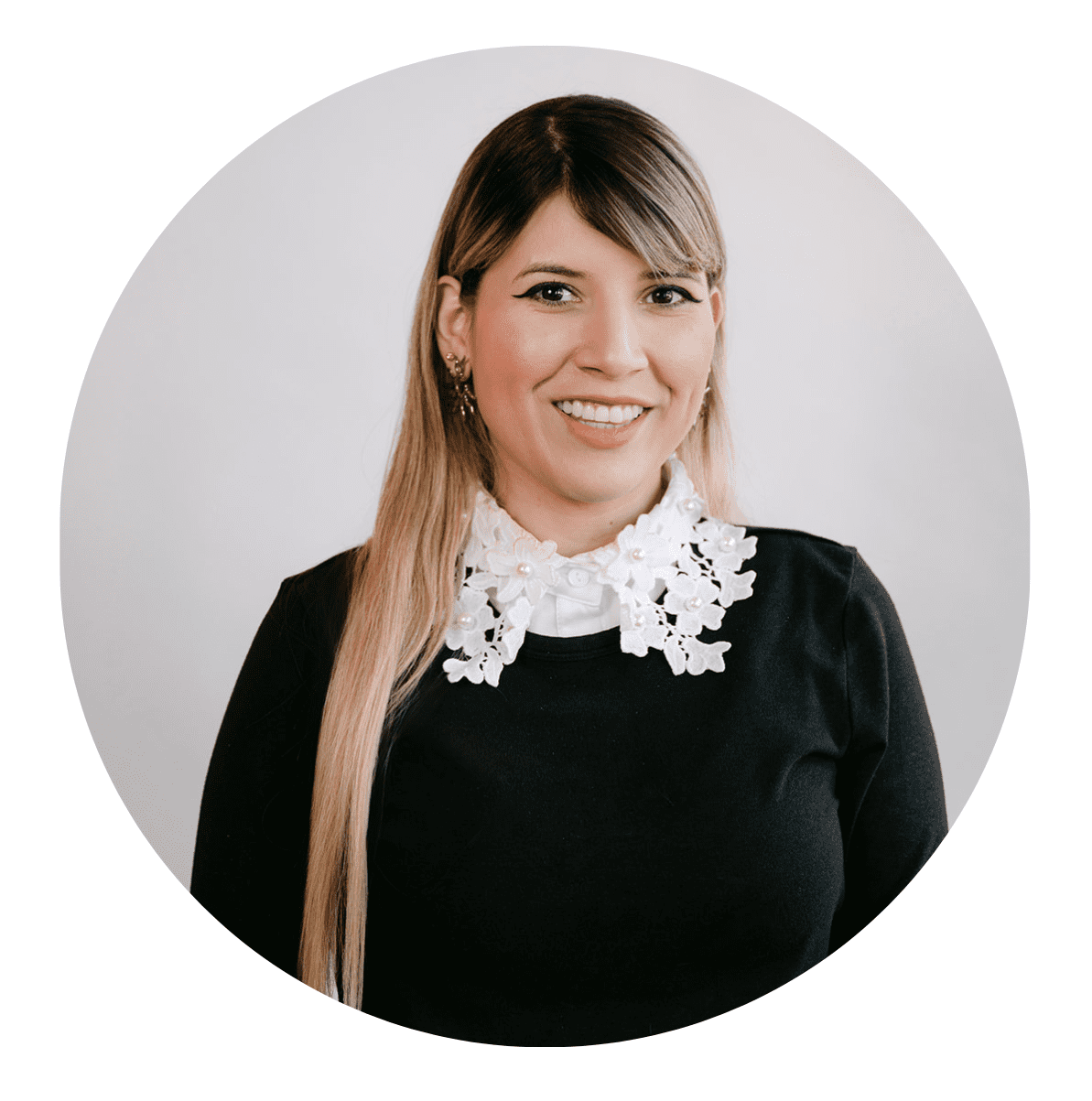 A woman with long, straight, light brown hair and side-swept bangs smiles at the camera. She wears a black top with a distinctive white lace collar, set against a plain white background—perfect for an About RMMFI profile photo.