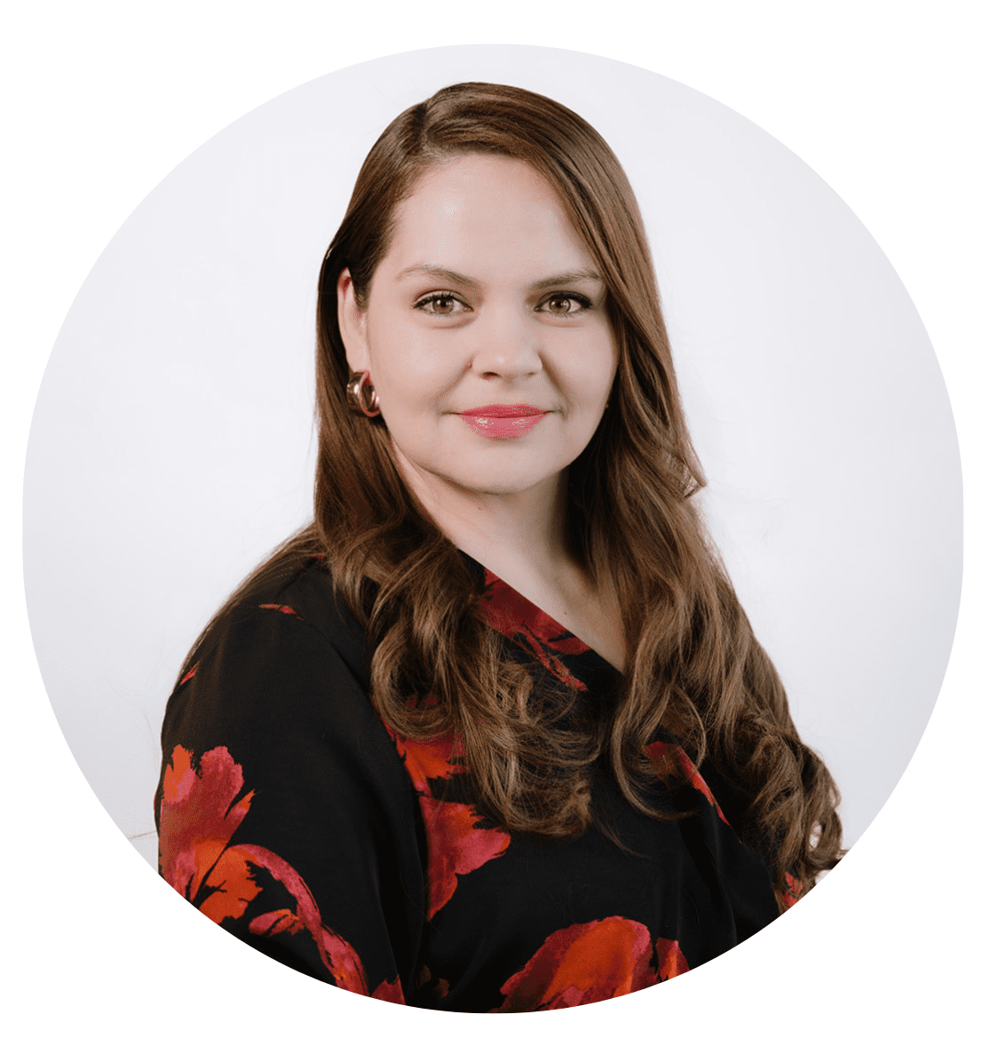 A woman with long brown hair, wearing a black top with red floral patterns, smiles and poses against a plain white background in a circular portrait frame, representing the friendly faces you'll find when learning more About RMMFI.